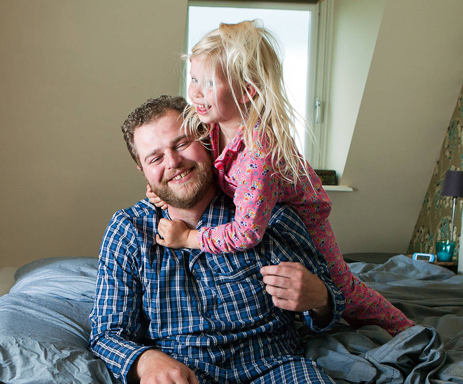 Uitgeruste vader door CPAP-therapie met zijn dochter op bed 