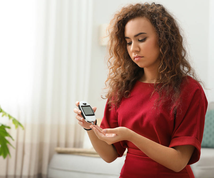 Jonge vrouw controleert haar bloedglucosewaarden thuis