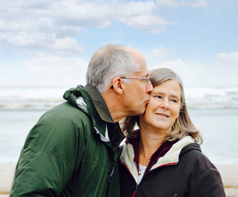 Ouder echtpaar wandelt over het strand en toont affectie