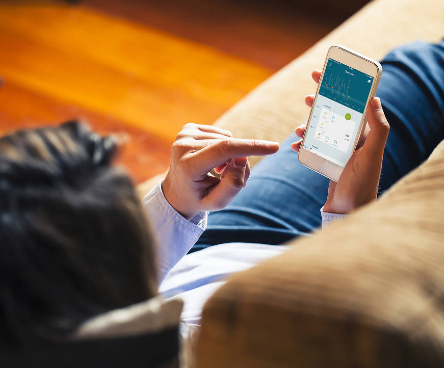 Diabetespatiënt ligt op bank en maakt gebruik van de DiaCare-app