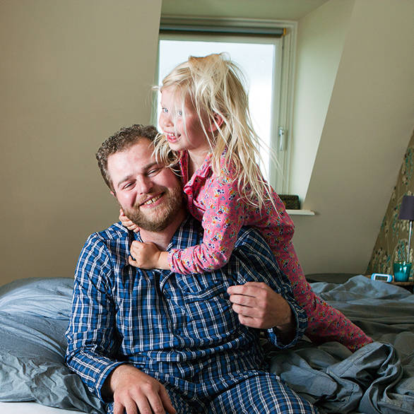Uitgeruste vader door CPAP-therapie op bed met zijn dochter