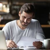 Man leest blad met laptop