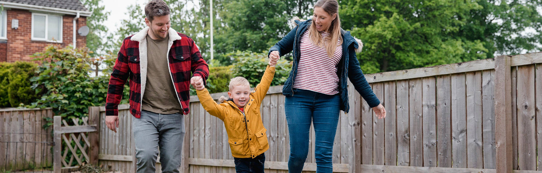 Vader, moeder en zoon spelen samen buiten in de tuin