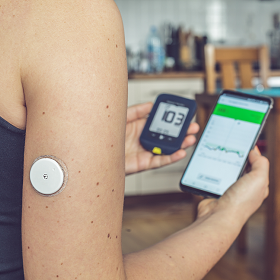 Iemand met diabetes vergelijkt glucosewaarden op een FreeStyle Libre reader en de app