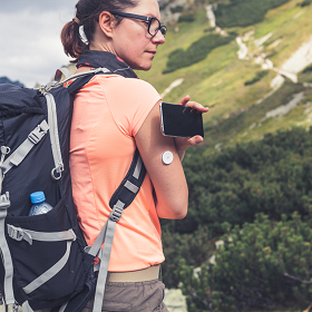 Vrouw met diabetes scant haar FreeStyle Libre sensor tijdens een wandeling in de bergen