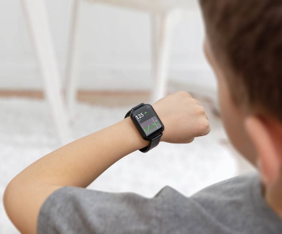 Jongen bekijkt diabetes glucosewaarde op zijn smartwatch