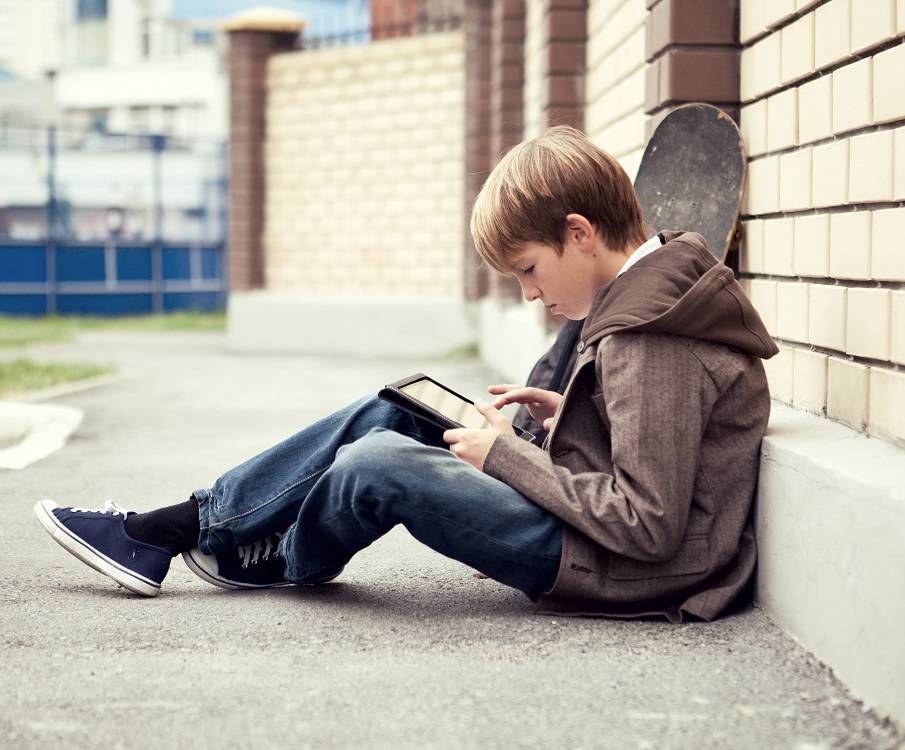 Tiener zit buiten op de grond met een tablet
