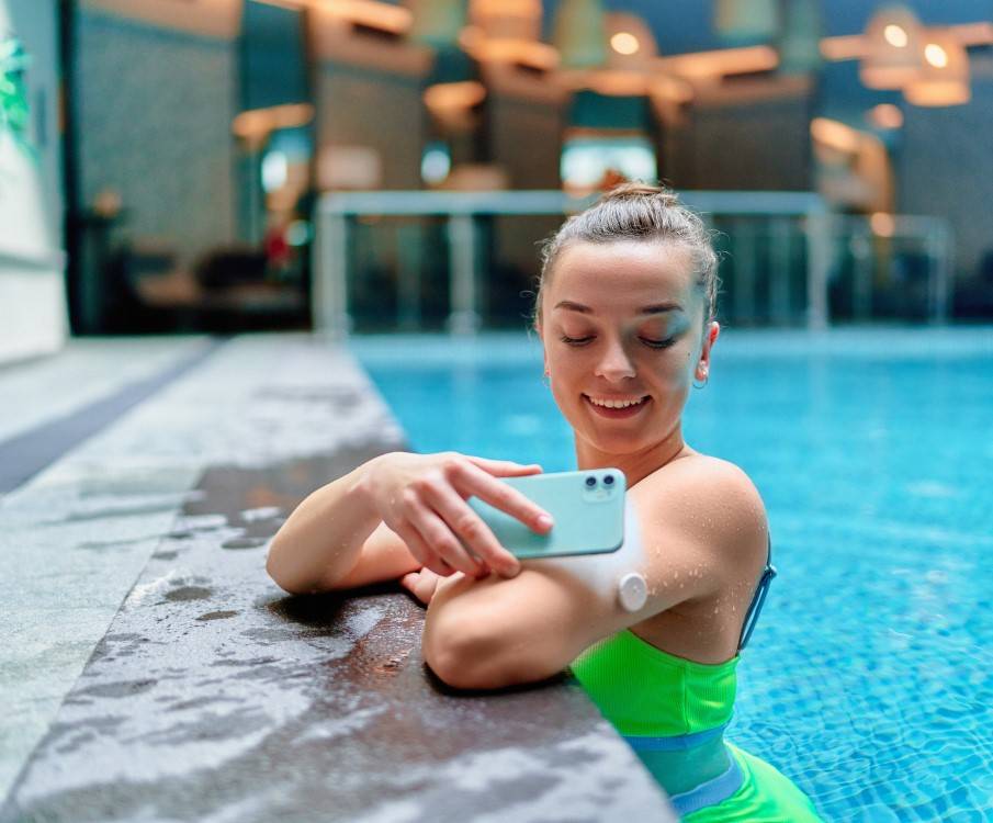 Vrouw controleert haar glucosewaarde op de glucosesensor in het zwembad