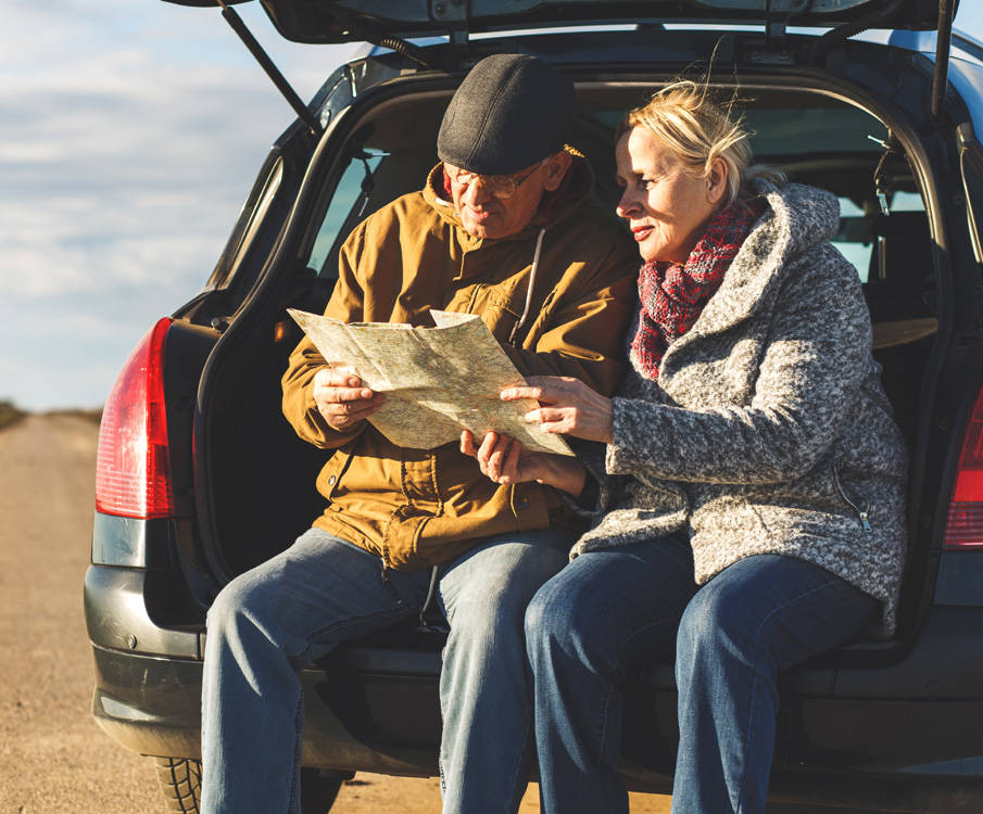 Man en vrouw zitten in auto en lezen een routekaart