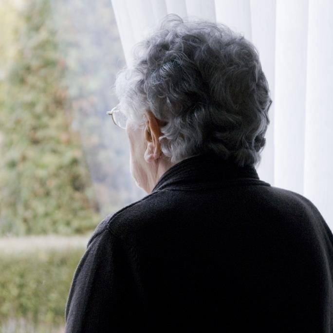 Eenzame seniore vrouw staart uit het raam