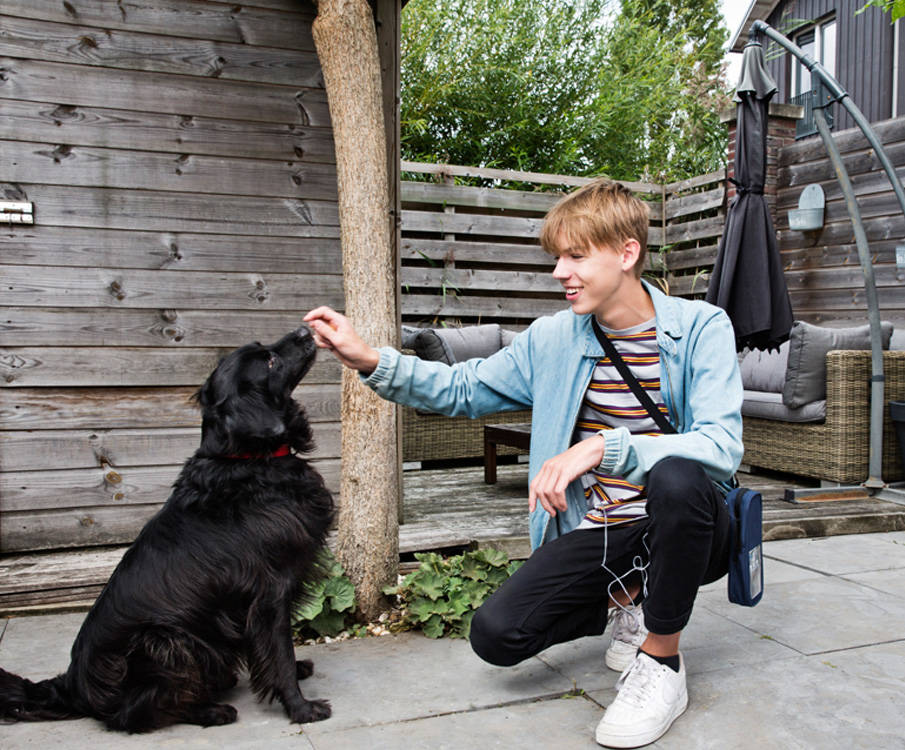 Jongen met hond draagt mobiele infuuspomp in tuin