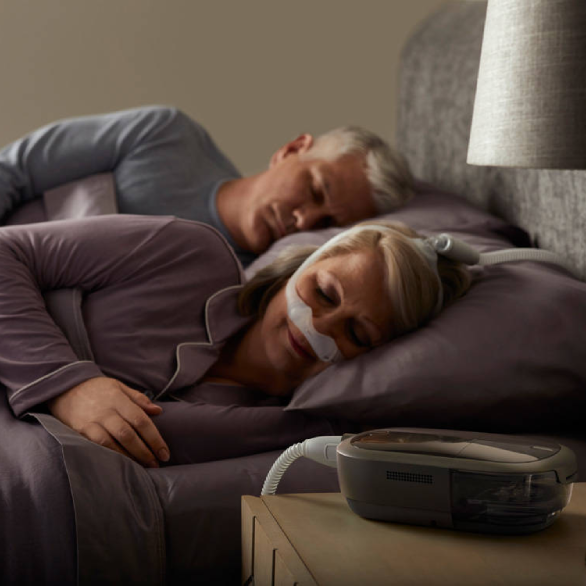 Vrouw slaapt met CPAP-apparaat Dreamstation 2 van Philips