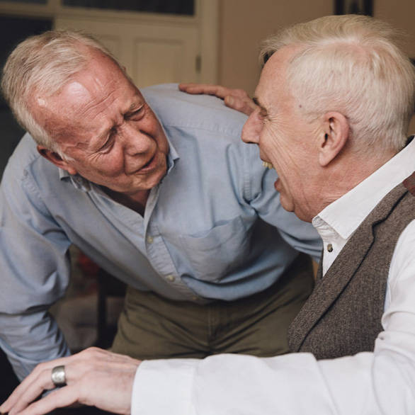 Twee lachende bevriende mannen bij elkaar thuis op visite