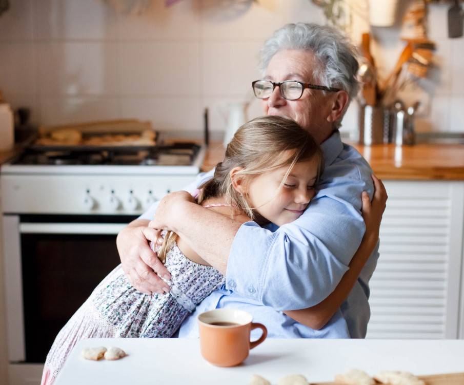 oma en kleindochter knuffelen elkaar in de keuken