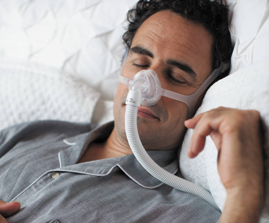Man slaapt in bed met een CPAP-masker