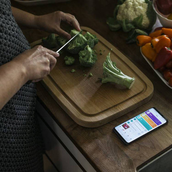 Vrouw snijdt in keuken groenten en krijgt begeleiding via de Mediq healthcoach app