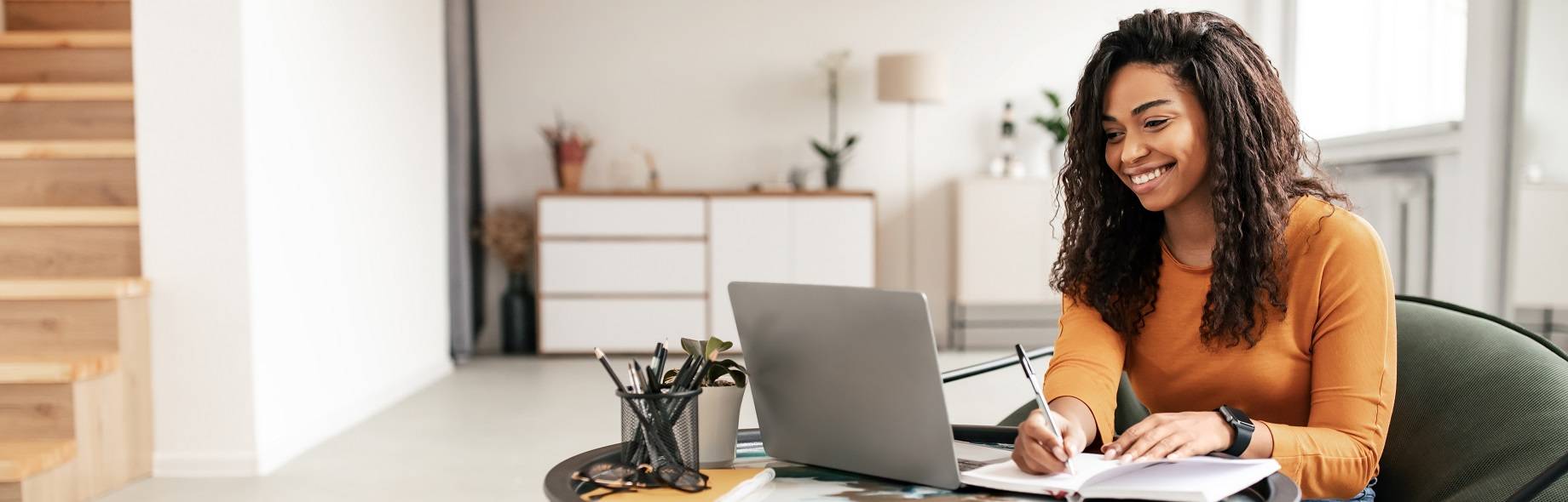 Vrouw achter laptop schrijft op