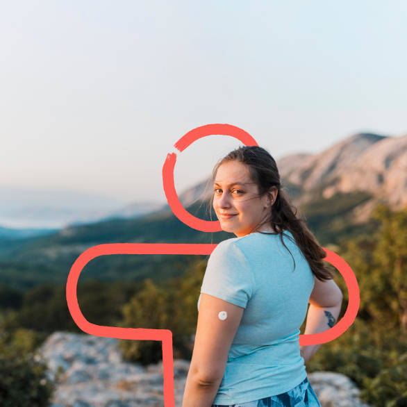 Vrouw met diabetes (met een sensor op haar arm) aan het wandelen, ze kijkt achterom