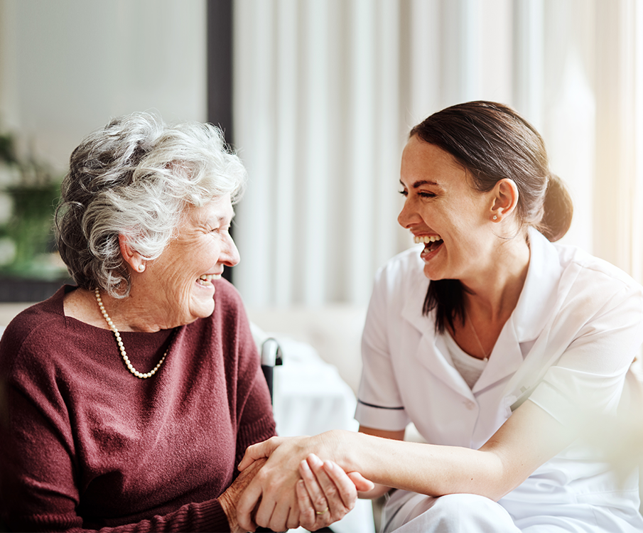 zorgmedewerker en een oudere vrouw lachen samen 