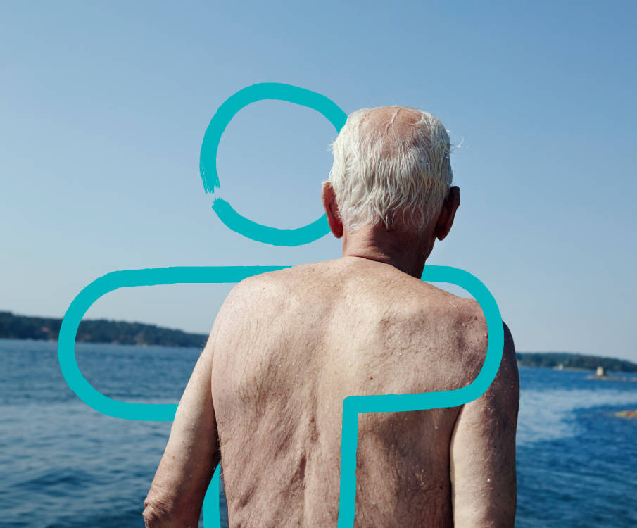 Oude man staat bij open water met zijn rug naar de camera.