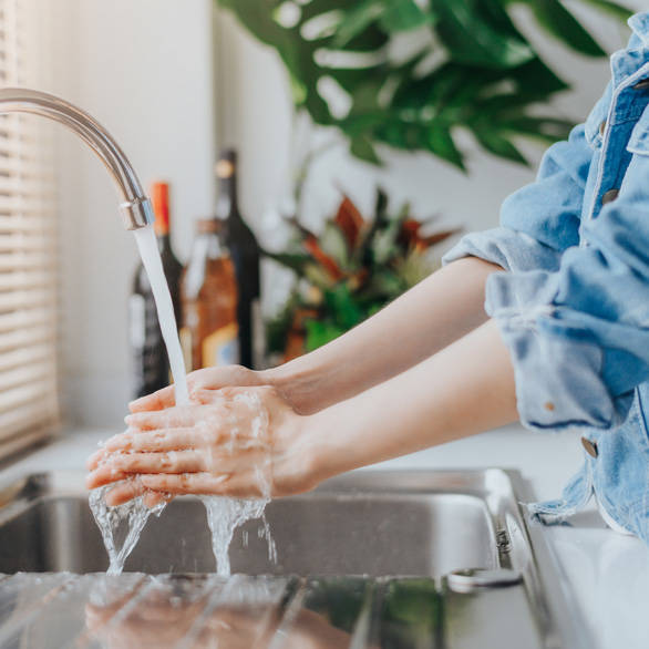Vrouw wast haar handen in de keuken voor een betere handhygiëne