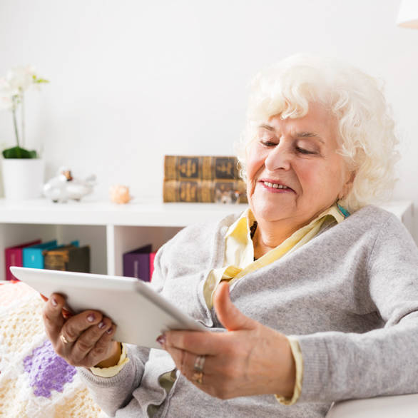 Oudere vrouw gebruikt tablet om te beeldbellen met zorgprofessional